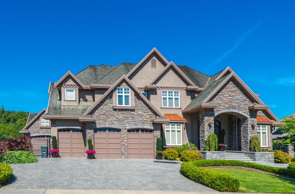 A custom-built luxury house with a well-maintained, neatly trimmed front yard lawn and landscaping.